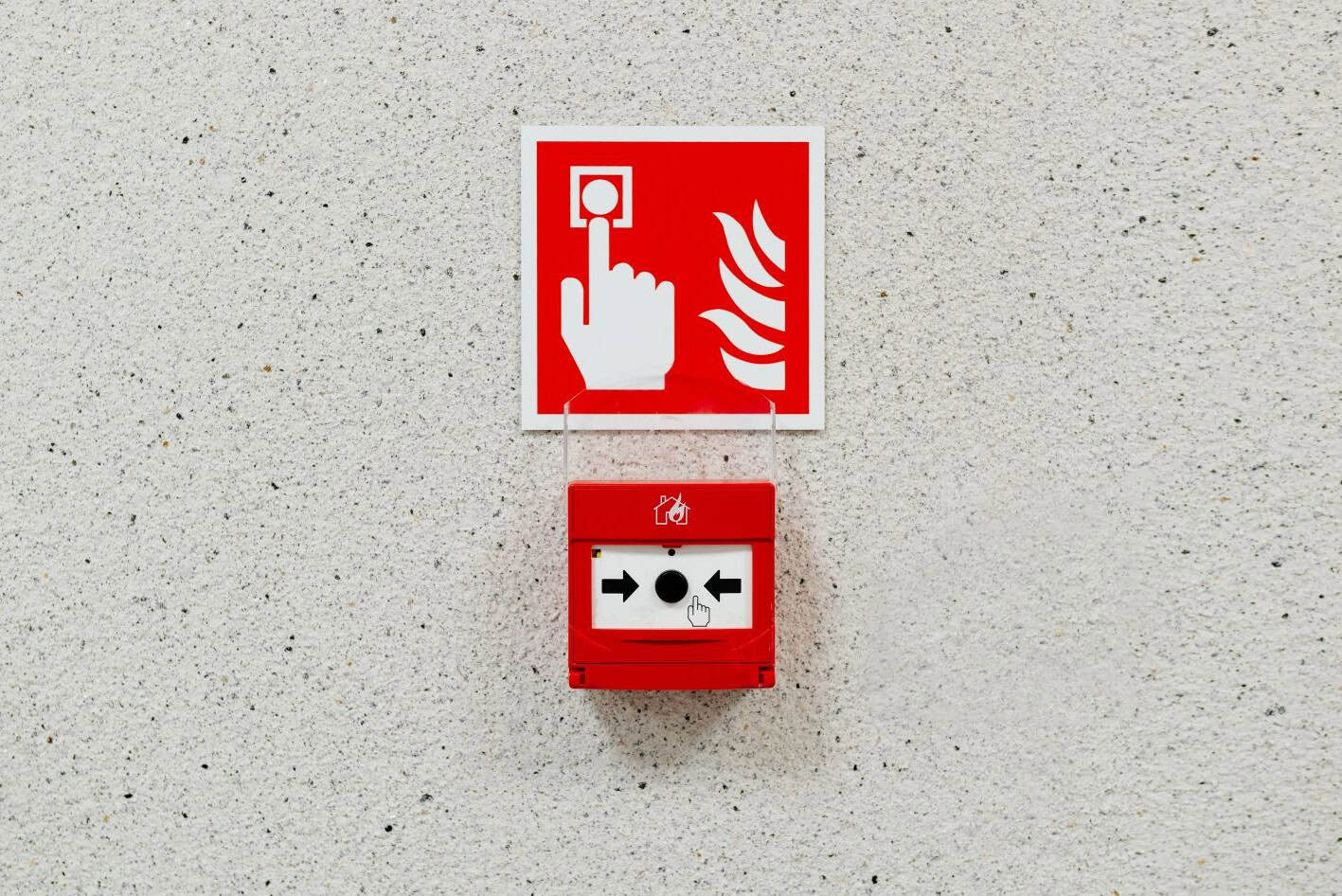 red fire alarm break glass button with sign above it